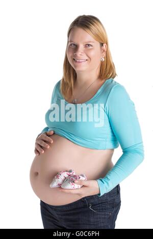 Kleine Schuhe für das ungeborene Kind in den Bauch der schwangeren Frau Stockfoto