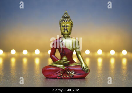 Buddha sitzt in der Meditation mit Kerze Stockfoto