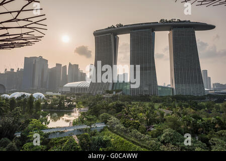 Blick auf die Marina Bay Sands Hotel bei Sonnenuntergang von der Supertree erhöhte Gehweg in Gardens by the Bay, Singapur Stockfoto