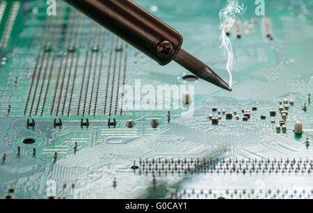 Rauchen Lötkolben auf einer Computer-Motherboard-Nahaufnahme Stockfoto