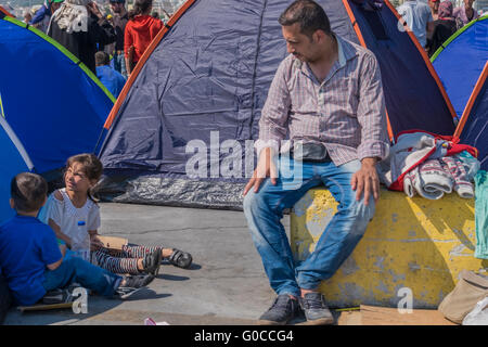 Syrischer Flüchtling Vater schaut auf seine beiden Kinder und wartet darauf, dass offizielle Verarbeitung von seinen Asylantrag in Lesbos, Griechenland Stockfoto