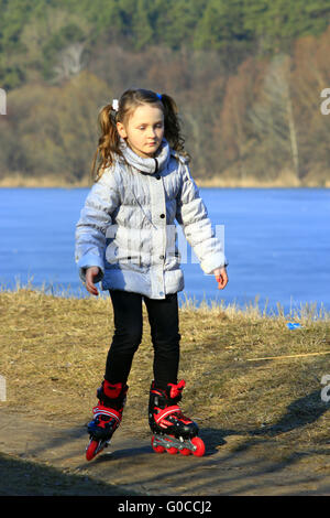 junges schönes Mädchen geht in Rollschuhe auf der Stockfoto