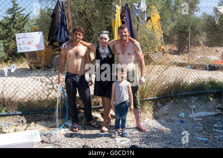 Nach Überfahrt aus der Türkei nach der Insel Lesbos in einem Schlauchboot mit 40 anderen genießen drei syrische Flüchtlinge eine Außendusche Stockfoto