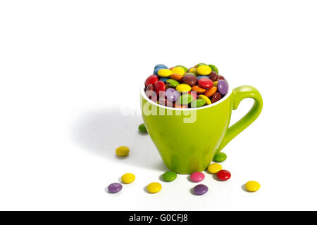 Bunte Dragees in kleinen grünen farbigen Tasse auf weiß Stockfoto