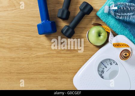 Fitness und Gewicht-Verlust-Konzept, Hanteln, Maßband, weiße Skala Handtücher und Wasser Flasche auf einem Holztisch, Ansicht von oben Stockfoto