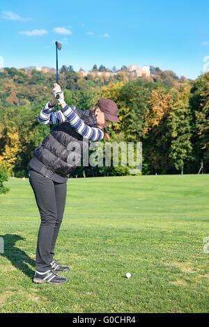 Junge Frau auf einem Golfplatz an einem sonnigen Herbsttag im Hintergrund des alten Schlosses Stockfoto