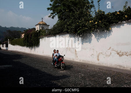 Die Einheimischen einen Motorroller in Antigua eine Stadt im zentralen Hochland von Guatemala berühmt für seine gut erhaltenen spanischen Barock geprägte Architektur und ein UNESCO-Weltkulturerbe. Stockfoto