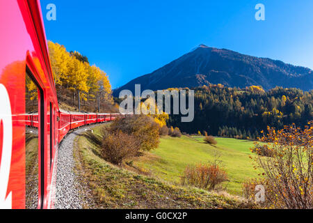 Reisen Sie mit dem Zug der Rhätischen Bahn im goldenen Herbst durch die Linie der Glacier Express im Engadin, Kanton Graubünden, Ausrüstu Stockfoto