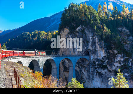 Der Zug der Rhätischen Bahn laufen auf dem berühmten Landwasser Viadukt in den Tunnel, an einem sonnigen Herbsttag, Kanton Graubünden Stockfoto