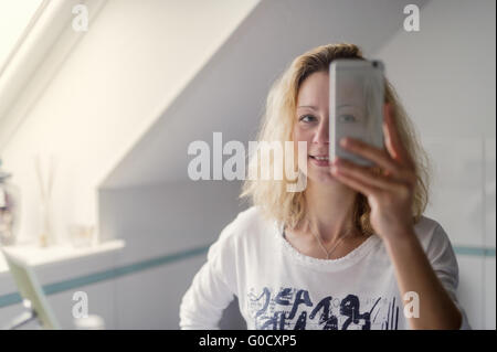 Junge Frau steht vor dem Badezimmerspiegel Stockfoto