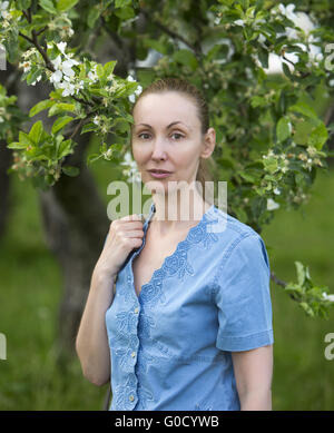 Frau stand in der Nähe des blühenden Apfelbaums Stockfoto