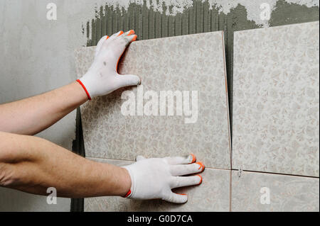 Fliesenleger, keramische Wand Fliesen in Position über Klebstoff. Stockfoto