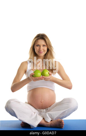 Schwangere Frau praktizieren Yoga und hält Äpfel Stockfoto