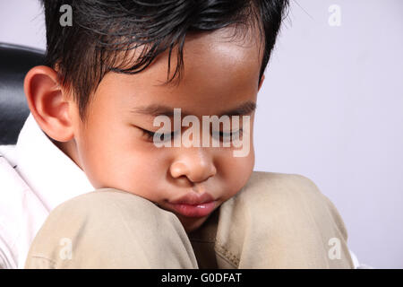 Porträt von traurig Asian Boy legte sein Gesicht auf die Knie Stockfoto