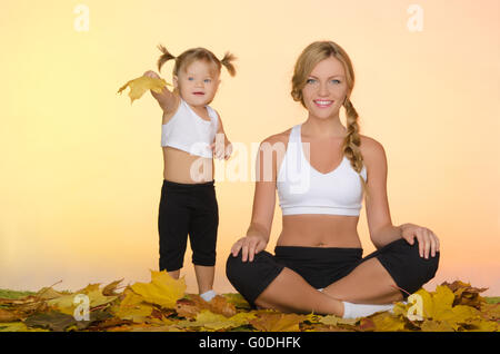 schöne Frau und Kind tun Yoga im Herbst Stockfoto