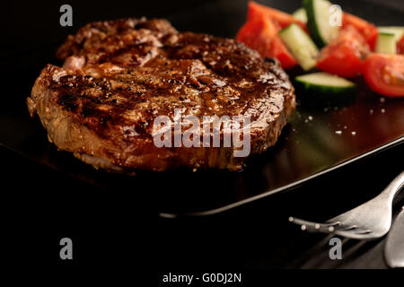 Gegrilltes Steak und Gemüse auf schwarze Platte mit Gabel Stockfoto