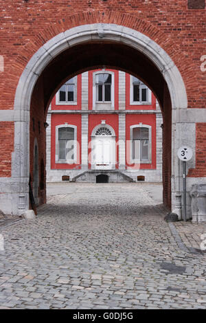 Gepflasterten Straße und das Tor mit dem Hauptgebäude der Stavelot Abbey durch einen Torbogen gesehen. Stockfoto