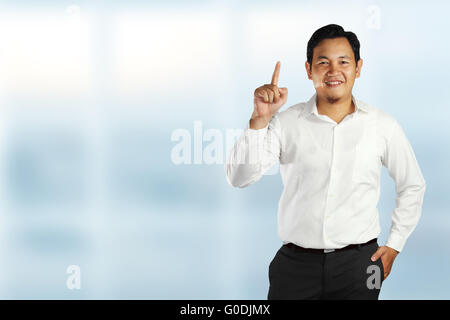 Junge asiatische Männer stehen und Lächeln, zeigt Nummer eins Geste mit seinem Zeigefinger auf hellem Hintergrund Stockfoto