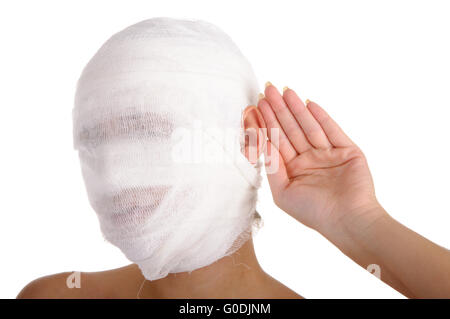 Junge Frau mit bandagiertem Kopf mit Palm an einem Ohr Stockfoto