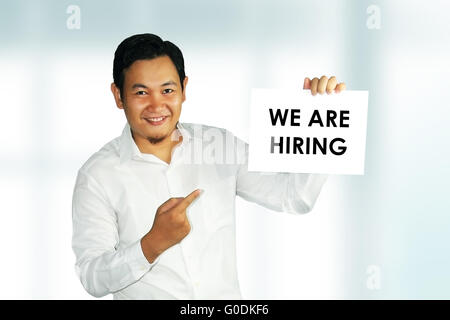 Bild von einem jungen asiatischen Mann holding Weißbuch mit wir suchen Worte über hellen Hintergrund drauf geschrieben Stockfoto