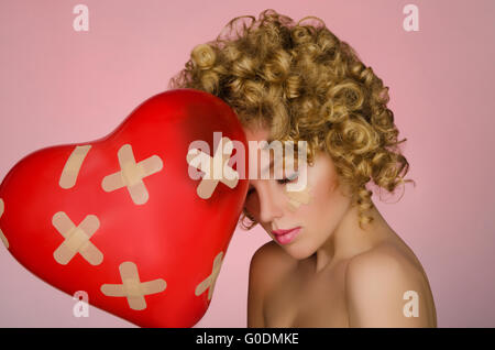 Ballon in Form von Herzen und junge Frau verletzen Stockfoto