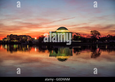 WASHINGTON DC, Vereinigte Staaten – das Jefferson Memorial reflektiert die stillen Gewässer des Tidal Basin im Licht der Dämmerung. Das neoklassizistische Denkmal, das 1943 fertiggestellt wurde, steht als stiller Wächter vor Sonnenaufgang. Die Marmorkuppel und die Säulen des Gedenkwerks erzeugen Spiegelbilder auf der Wasseroberfläche in den ruhigen frühen Morgenstunden. Stockfoto