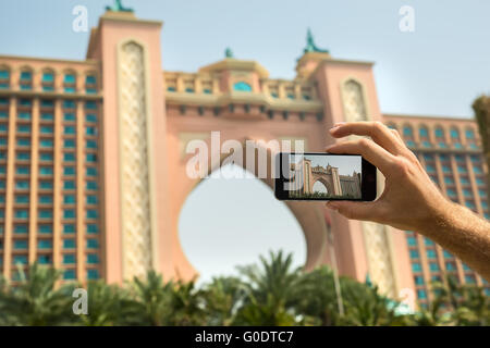 Hand-Tourist nimmt ein Bild des Hotel Atlantis Dubai auf Handy Stockfoto