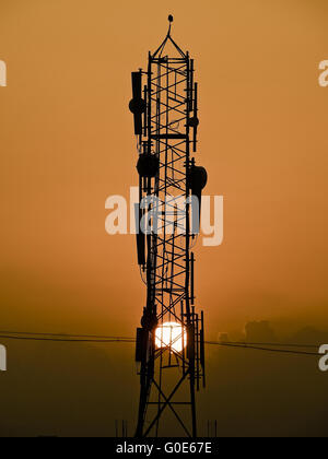 Sonnenuntergang gegen eine mobile Gesellschaft erhebt sich zum mobilen Signal empfangen Stockfoto