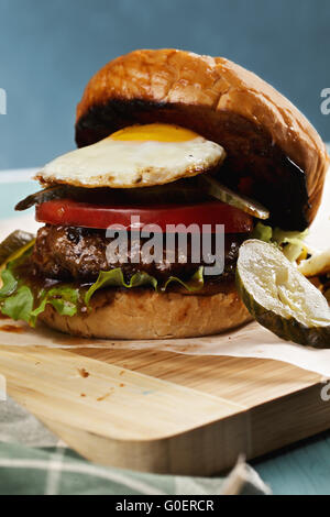 Burger, garniert mit sonnigen Ei auf einem Holzbrett closeup Stockfoto