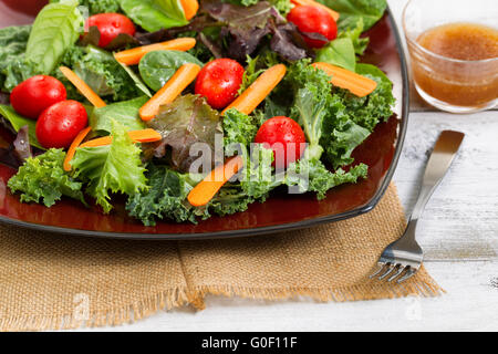 Gesunden grünen Salat auf dunklen Teller mit rustikalen hölzernen Tafeln Stockfoto