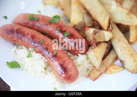 Zwei Würste auf Sauerkraut mit einer Seitenlänge von Pommes frites Stockfoto