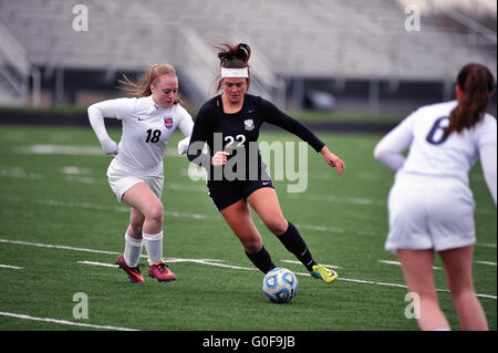 Mittelfeldspieler Dribbling unter die gegnerische Verteidigung mit beim Versuch, einen Schuß auf Ziel während der High School Fußball Spiel erhalten. USA. Stockfoto