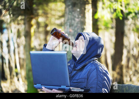 Mann mit Bierflasche und PC im park Stockfoto