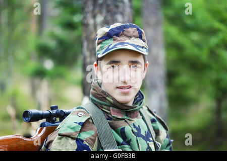 Jugendlichen zu rekrutieren, mit optischen Gewehr im Wald Stockfoto