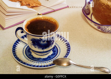 Eine Tasse schwarzen Kaffee und Kuchen auf dem Tisch. Stockfoto