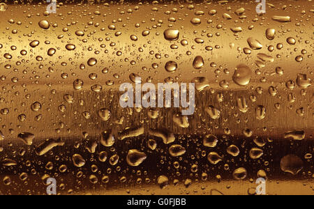 Gold-Platte mit Wasser tropft auf die abgerundete Oberfläche. Hintergrund Stockfoto