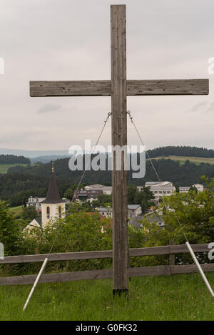 Holzkreuz steht vor Landgemeinde Stockfoto