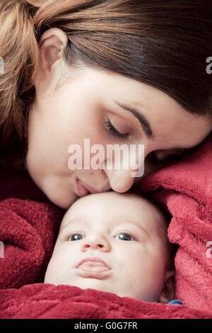 Mutter mit jungen Baby kuscheln und küssen ihn auf die Stirn. Elternschaft Stockfoto