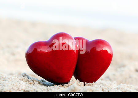 Zwei rote Herzen am Strand als Symbol für Liebe Stockfoto