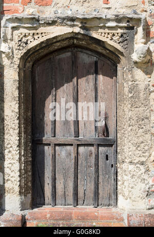 Eine alte Holztür mit Stein in der Mauer der Kirche in England umgeben. Stockfoto