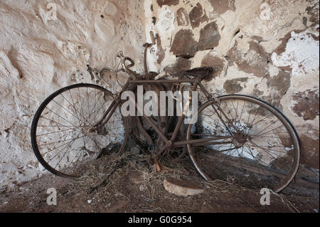 Ein altes rostiges Fahrrad in die Ecke von einem alten steinernen Schuppen aufgestützt. Stockfoto