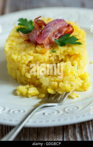 Safran-Risotto mit Speck und Petersilie garniert. Stockfoto