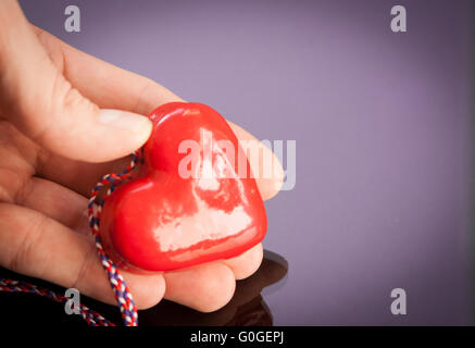 des Mannes Hand, die ein rotes Herz Stockfoto