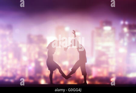 Glückliches Paar in Liebe Herzform machen. Stadt bei Nacht Hintergrund. Stockfoto