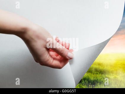 Hand zieht eine untere Papierecke aufzudecken Stockfoto