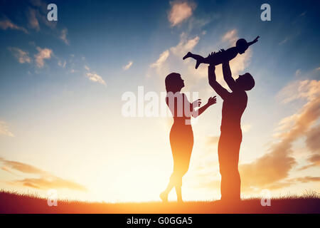 Glückliche Familie zusammen, Eltern mit ihrem kleinen Kind bei Sonnenuntergang. Stockfoto