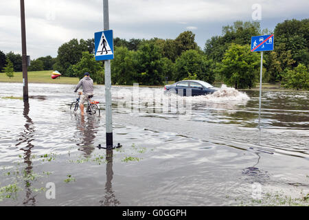 Radsport Mann und Auto versucht, gegen die Flut auf der Straße fahren. Stockfoto