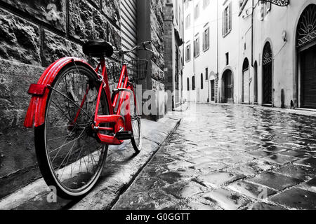 Retro Vintage rotes Fahrrad auf der Straße mit Kopfsteinpflaster in der Altstadt. Farbe in schwarz und weiß Stockfoto