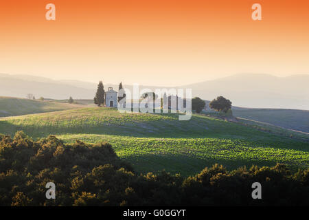 Toskana-Landschaft bei Sonnenaufgang mit einer kleinen Kapelle der Madonna di Vitaleta, Italien. Stockfoto