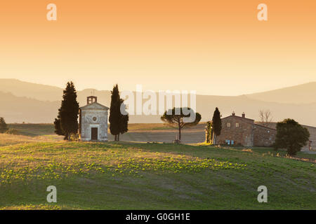 Toskana-Landschaft bei Sonnenaufgang mit einer kleinen Kapelle der Madonna di Vitaleta, Italien. Stockfoto